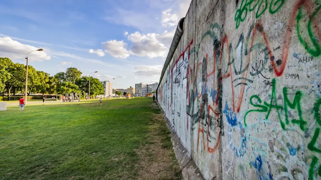Ein Blick auf die Berliner Mauer mit Graffiti und angrenzender Grünfläche.
