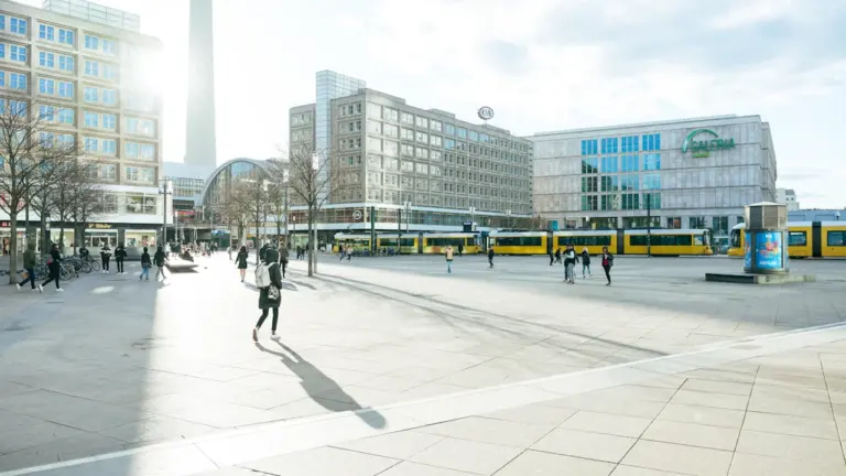 Der moderne Alexanderplatz in Berlin mit Straßenbahn und umliegenden Gebäuden bei Tageslicht.