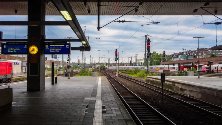 Moderner Bahnsteig mit Gleisen und Oberleitungen an einem trüben Tag in Deutschland.