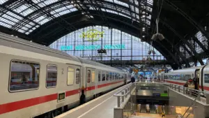 Ein einfahrender Zug im Kölner Hauptbahnhof mit historischen Elementen im Hintergrund.