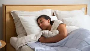 Eine junge Frau schläft friedlich in einem hellen, aufgeräumten Schlafzimmer.