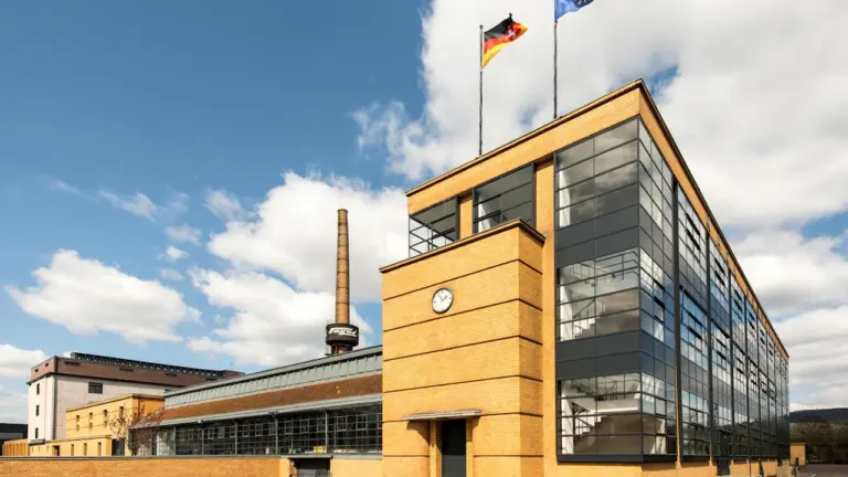 Ein Fabrikgebäude in Deutschland mit einer wehenden deutschen Flagge am helllichten Tag.