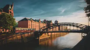 Historische Speicherstadt in Hamburg mit Brücke und dramatischem bewölktem Himmel bei Sonnenuntergang.