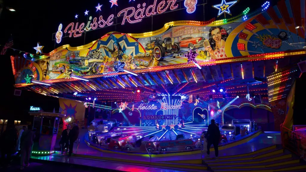 Buntes Fahrgeschäft auf einem Jahrmarkt bei Nacht mit heller Beleuchtung.