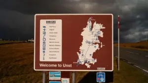 Ein Hinweisschild mit einer detaillierten Regionalkarte an einer Straße bei bewölktem Wetter.