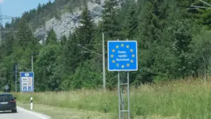 Ein blaues EU-Grenzeingangsschild an einer bewaldeten Landstraße in Deutschland.
