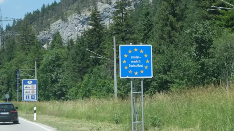 Ein blaues EU-Grenzeingangsschild an einer bewaldeten Landstraße in Deutschland.