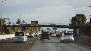 Autos auf einer Autobahn mit Verkehrsschildern bei Tageslicht zur Ferienreisezeit.