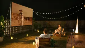 Paar schaut nachts einen Film bei einer Open-Air-Kinoveranstaltung im eigenen Garten.