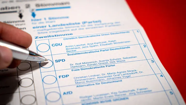 Eine Hand füllt einen Wahlzettel aus und markiert die SPD bei der Wahl.