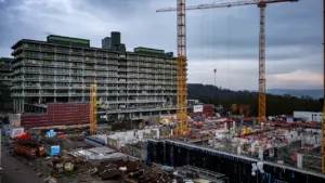 Baukran über einer großen Baustelle mit einem im Bau befindlichen öffentlichen Gebäude.