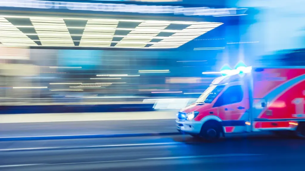Ein Rettungswagen im nächtlichen Einsatz mit Blaulicht auf einer deutschen Straße.