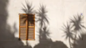 Geschlossene Fensterläden an einer Hausfassade bei sonnigem Wetter zur Hitzeprävention.