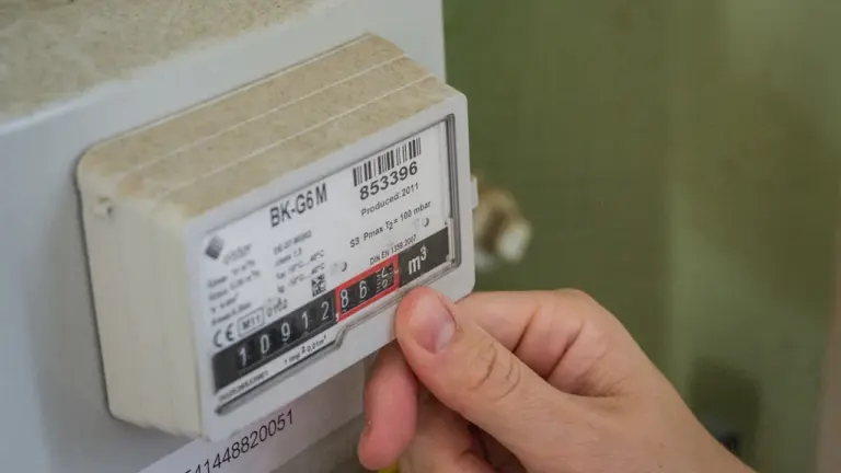 Eine Hand beim Ablesen des Stromverbrauchs an einem digitalen Stromzähler im Haushalt.