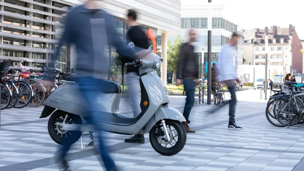 Elektroroller auf städtischem Platz während der Europäischen Mobilitätswoche mit bewegten Passanten im Hintergrund