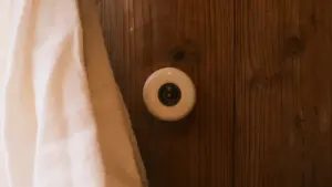 Weißer Keramik-Türknauf an einer rustikalen Holztür im Innenbereich eines Wohnhauses.