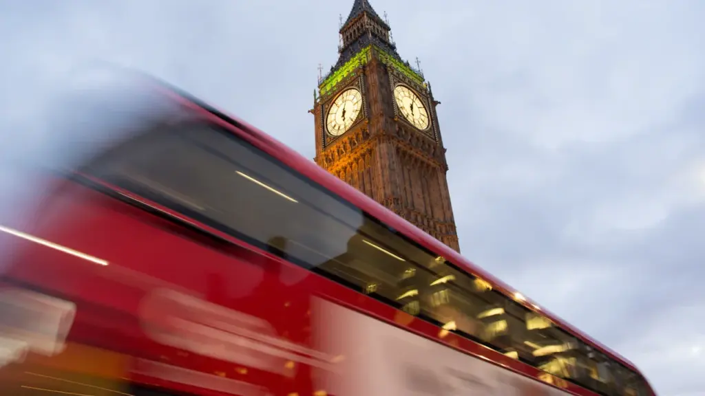Ein roter Doppeldeckerbus fährt an der berühmten Elizabeth Tower Uhr in London vorbei.