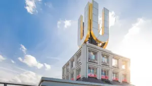 Das ikonische, beleuchtete goldene U-Symbol auf dem Dach des Dortmunder U-Turms bei Sonnenschein.