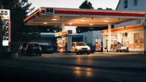 Eine typische deutsche Tankstelle bei Dämmerung mit mehreren parkenden Autos und Preisanzeige.