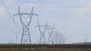 Strommasten und Windräder auf einem Feld als Symbol für die Energiewende in Deutschland.