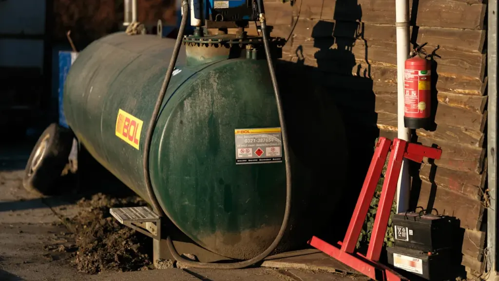 Ein großer grüner Heizöltank steht sicher neben einem Gebäude auf dem Land.