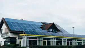 Ein typisches deutsches Wohnhaus mit einer Photovoltaikanlage auf dem Dach bei Tageslicht.